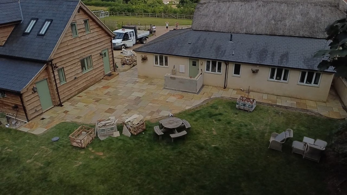 Aerial view of the timber-clad building and slate-roofed extension with the new sandstone patio