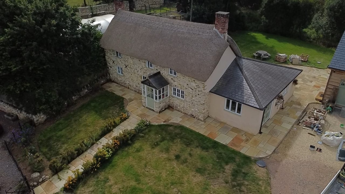 Aerial view of a thatched stone cottage with new Indian sandstone paving and paths around the garden