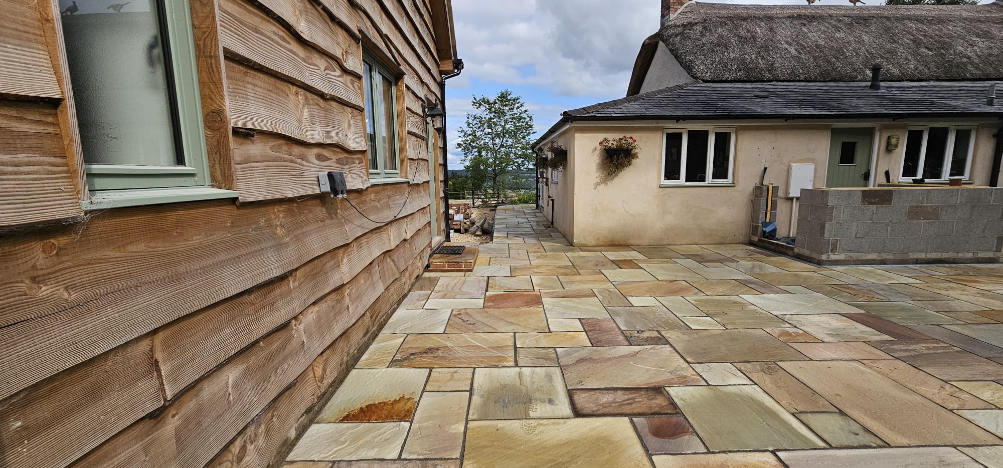 Indian sandstone paving laid around a timber-clad property in Yarcombe, Devon