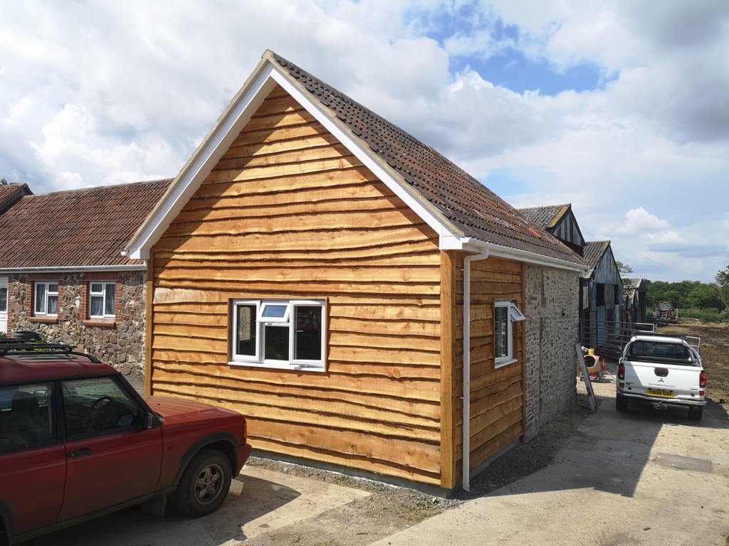 A completed timber-clad house extension with a pitched tiled roof