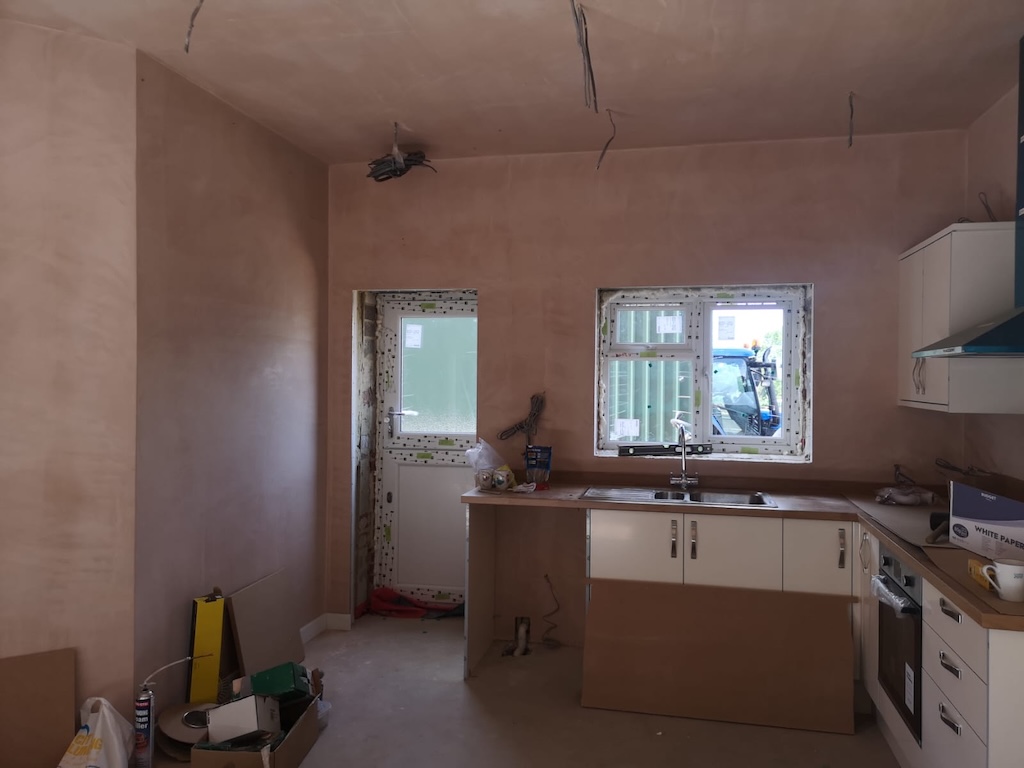 The kitchen area freshly plastered, with units fitted and windows installed