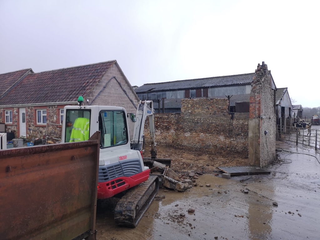 An excavator clearing the site during demolition and groundworks