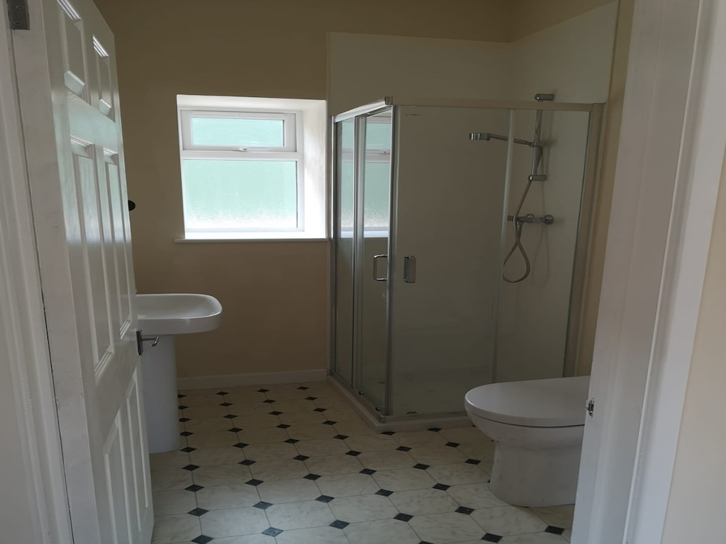 The completed bathroom with a shower enclosure, basin and tiled floor