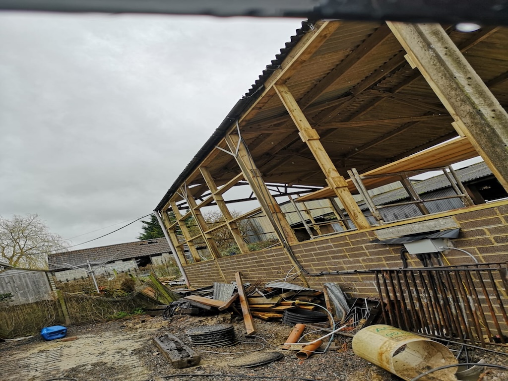 The original barn before work, with a damaged timber frame and failed roof sheets